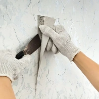 Worker repairing torn wall wallpaper